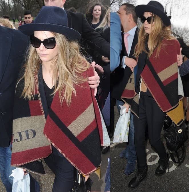 Cara Delevingne wears a wrap monogrammed with her name as she leaves the Burberry show during London Fashion Week