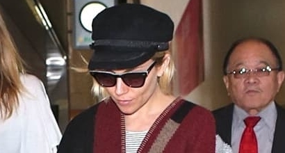 Sienna Miller’s Travel Style: Cozy and Chic in Sweatpants, Gray Sweater, and Personalized Burberry Blanket Wrap